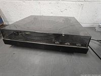 Left front angle of Gemini turntable with dust cover closed showing rectangular shape and black body.