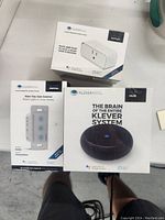 Photo showing three Kleverness smart devices in their boxes: Outlet, Switch, and Hub