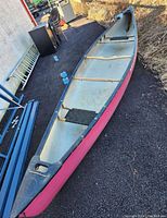 Overhead view of canoe interior showing wooden thwarts, black webbed seat and dirt accumulation