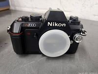 Front view of Nikon N2000 black 35mm SLR film camera body with lens mount cap attached.
