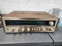 Front view of Onkyo TX-8500 solid state receiver showing tuning dial, volume control, and multiple knobs for bass, treble, balance, and function selection with wood veneer top and side panels.