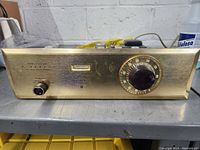 Front view showing gold front panel with tuning dial, selector knob, and meter window.