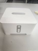 Front view of white Sonos Port showing control buttons and Sonos logo on top.