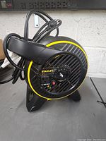 Frontal view of Stanley ball fan showing black and yellow color, front protective grille, Stanley logo, and missing control knob on front.