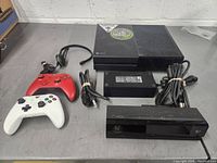 Xbox One console with Kinect sensor, 2 controllers, headset, power cables arranged on surface