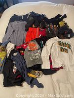 Photo of the full lot of boys clothes sizes 2-6 showing an assortment of tops, shorts, hoodie, underwear, and pants in various colors and prints.