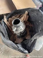Used garbage disposal unit placed inside a trash bag with cardboard packing around it.