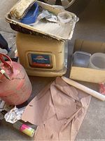 Plastic hooded cat litter box with scoop and blue litter tray insert among other tools and containers.