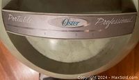 Close-up of the Oster logo with Portable and Professional markings on the dome hood of the hair dryer.