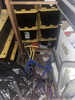 Teeter totter with blue metal frame and red seats in storage among other household items and plastic storage bins