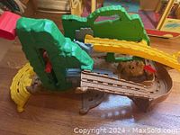 Thomas the Train parts assembled showing green plastic mountain, yellow track sliding section, and brown curved and straight tracks.