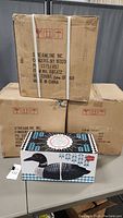 Three cardboard boxes stacked with one Streamline loon bookend set box on table in front, showing packaging and quantity.