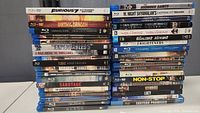 Pile of 38 Blu-ray movie cases stacked, front sides partly visible, showing a variety of action and thriller movie titles.