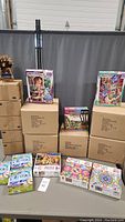 Photo showing stacked boxes and various puzzle boxes on a table including Rapunzel, Aladdin, and other puzzle themes.