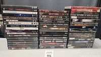 Full view of 54 DVD movie lot including visible titles in stacks, showing condition and quantity