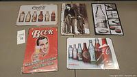 Overview of 5 new metal tin signs with vintage advertising themes displayed on table.
