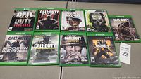 Photo of 9 Xbox One Call of Duty game cases arranged in two rows, showing their front cover art.