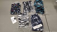 Six pairs of ladies plus size leggings, each in plastic packaging, assorted patterns including spots, abstracts, zebra and tie-dye.