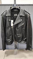 Front view of black leather FMC biker jacket hanging, showing asymmetrical zip closure, zippered pockets and epaulets.
