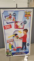 Front view of the sealed Buzz Lightyear Star Command Center box showing a boy playing with the toy in its various play modes including phone mode, desk mode, and launch mode.