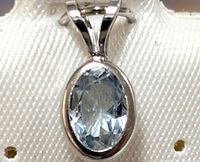 Close-up image of oval aquamarine gemstone set in smooth bezel 14K white gold setting, showcasing gemstone details and setting condition.