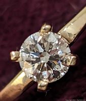 Front view close-up of round brilliant diamond set in four-claw 10k yellow gold band