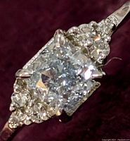 Front view of ring showing cushion cut center stone and surrounding round stones