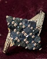 Close-up image of the ring showing the sapphire and white topaz stones in a marquise cluster design with detailed silver band.