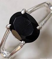 Close-up of sterling silver ring with faceted black onyx stone showing front detail and prong setting.