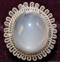 Close-up front view of the sterling silver ring with large oval moonstone cabochon showing the intricate looped border and clarity of the stone.