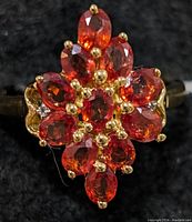 Top view of the ring showing detailed cluster of orange sapphire stones with gold prongs.