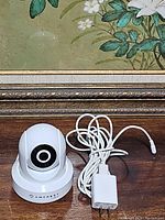 Front view of the Amcrest IP2M-841W ProHD 1080P Wireless WiFi IP Camera showing camera lens and white body with power adapter cable.