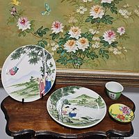 Photo showing all four items together: two round plates, a small porcelain cup/bowl, and a decorative floral brass and porcelain shallow bowl