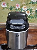 Front view showing stainless steel body, black control panel, and top window of the Igloo ice maker.