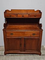 Front view of the hutch buffet with drawers and closed cabinet doors, showing brass hardware.