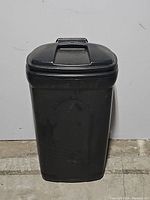 Front full view of the large black wheeled trash can showing the hinged lid and integrated handle on top.