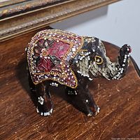 Front view of the jeweled elephant figurine showing detailed beadwork, sequins, and mirror pieces forming patterns on the body and ears.