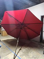 Full view of the opened red patio umbrella with metal pole and ribs. Shows size and condition of the umbrella.