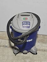 Front and angled views of the blue and gray Shop-Vac wet/dry vacuum with flexible hose attached, showing labels and overall condition.