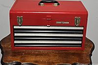 Closed red Craftsman toolbox with handle and two metal latch locks on front