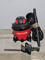 Craftsman wet/dry vacuum with hose attachments and Black & Decker hedge trimmer shown together.