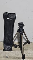 Full view of Velbon tripod extended with attached carrying case showing tripod legs and holding bag with Velbon logo.