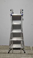 Front view of the closed ladder showing aluminum steps and frame with blue locking parts.