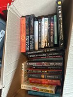 Top view showing the spines and front covers of the books in the box, revealing titles like 'Chasing New Horizons,' 'Bitcoin Billionaires,' and others.