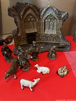 Photo showing the assembled and scattered nativity figurines including the stable, wise men, Mary, donkey, sheep, and baby group.