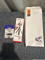Lot items on a dark textured surface: Verbatim USB drive in package, MobiFoto boxed tripod, and large plain white box with Playstation Portal Remote Player label.