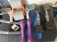 Exercise lot showing white ab roller, two black 8 lb dumbbells, two purple 5 lb dumbbells