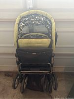 Front view of double stroller showing patterned fabric canopy and seats, four double wheels and storage basket underneath