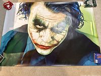 Photo of the full Joker poster laid out flat on floor, displaying the character from shoulders up with light and shadow details.
