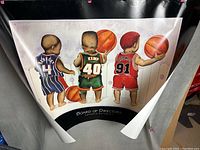 Full view of the large Kenneth Gatewood print showing three toddlers in basketball uniforms, curled and damaged at the top edges.